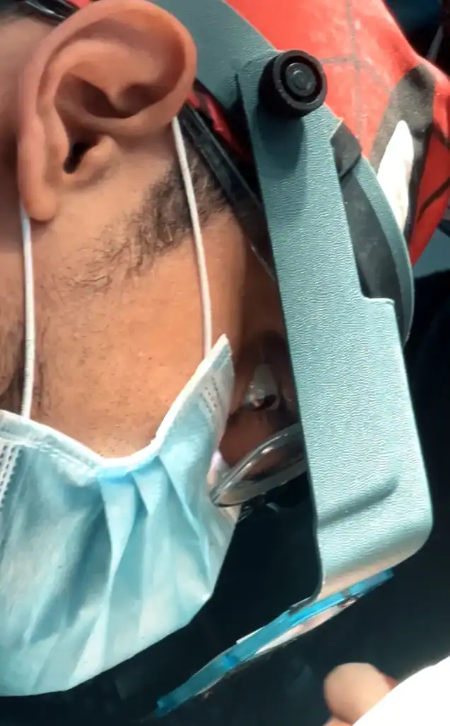 Close-up of a healthcare professional wearing protective gear, including a mask and goggles, prepari.